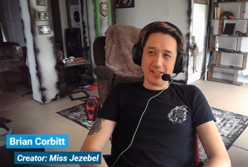 asian man wearing black t-shirt and headphones with tattoo on his arm, sitting in a living room