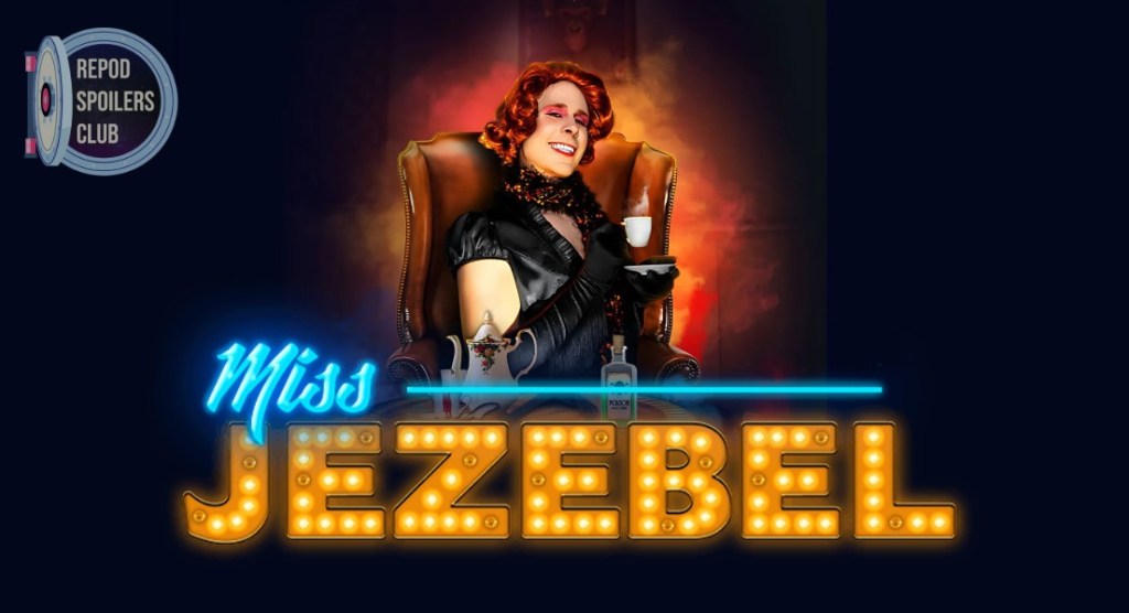 image of man in drag with red wig and black dress and scarf, smiling mischievously, holding a cup of tea