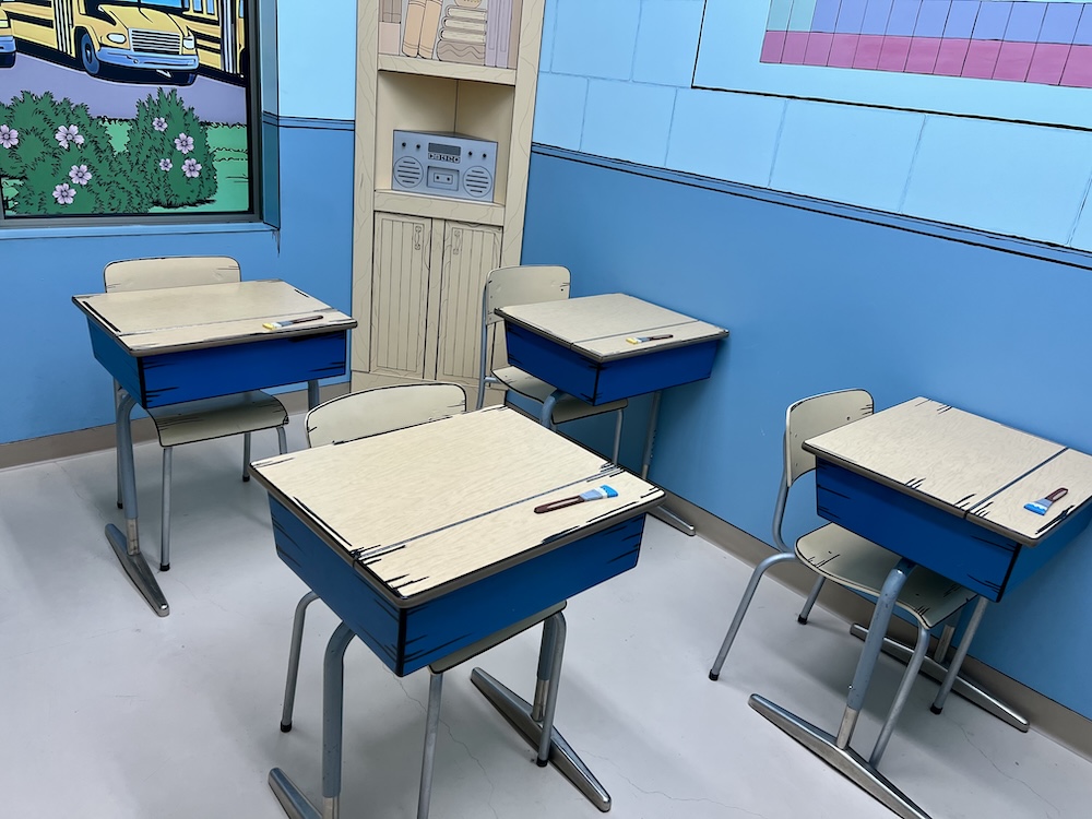 A classroom filled with school desks. Everything looks illustrated.