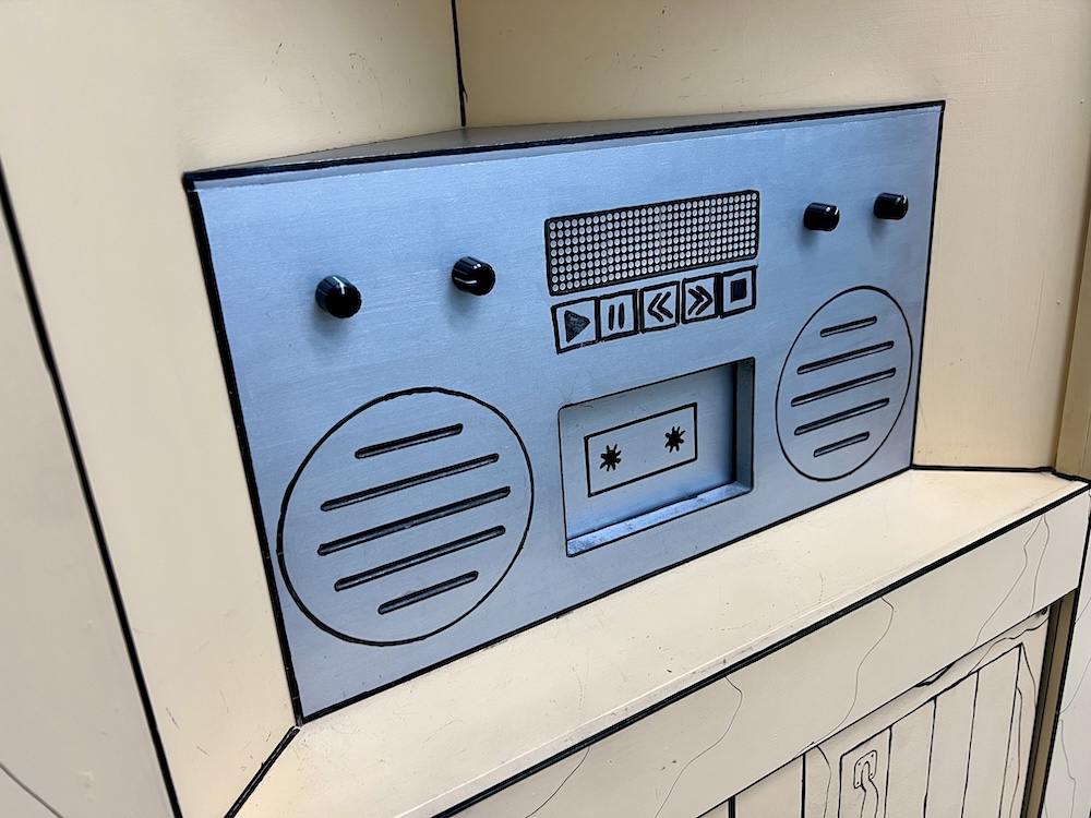A large, silver boombox that looks like it has been illustrated. There is a spot in the front for a cassette tape.