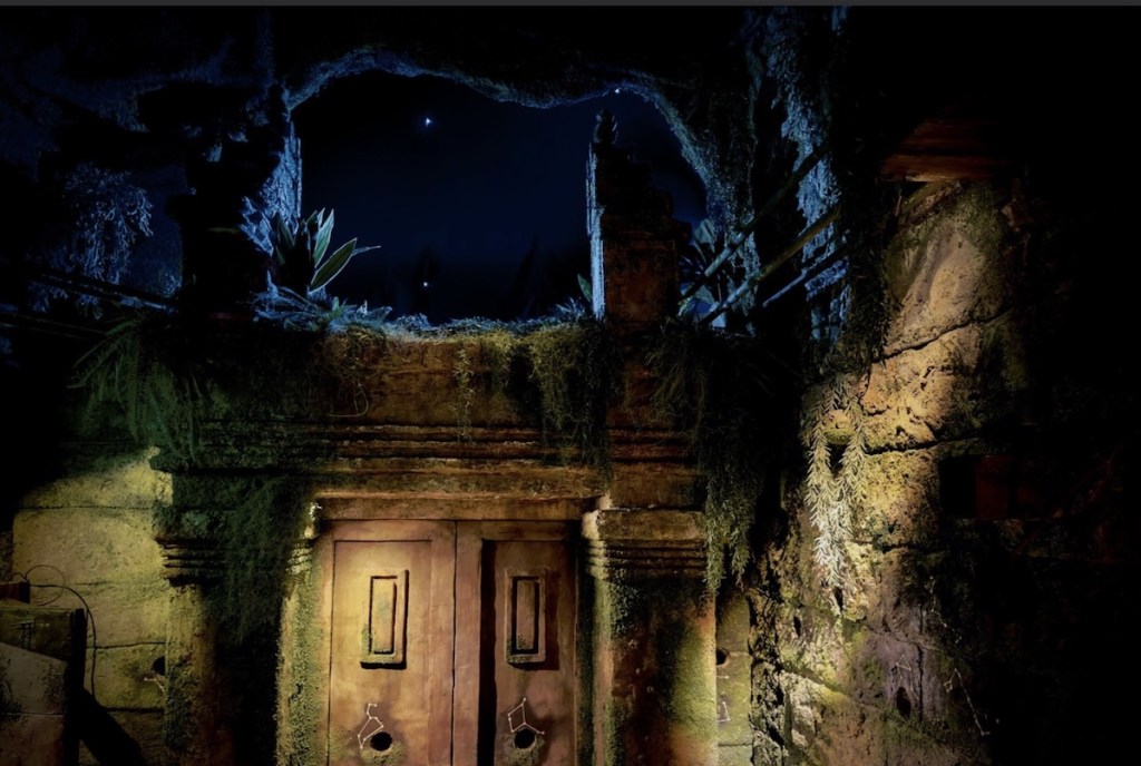 A hole in a temple wall looking out upon the night sky.