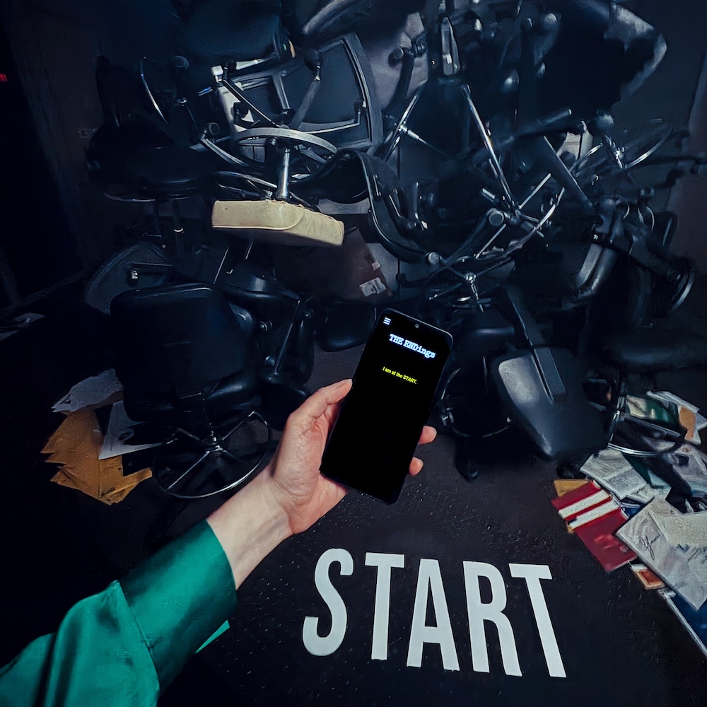 A hand holding a mobile phone over a stack of desk chairs and the word, "START."