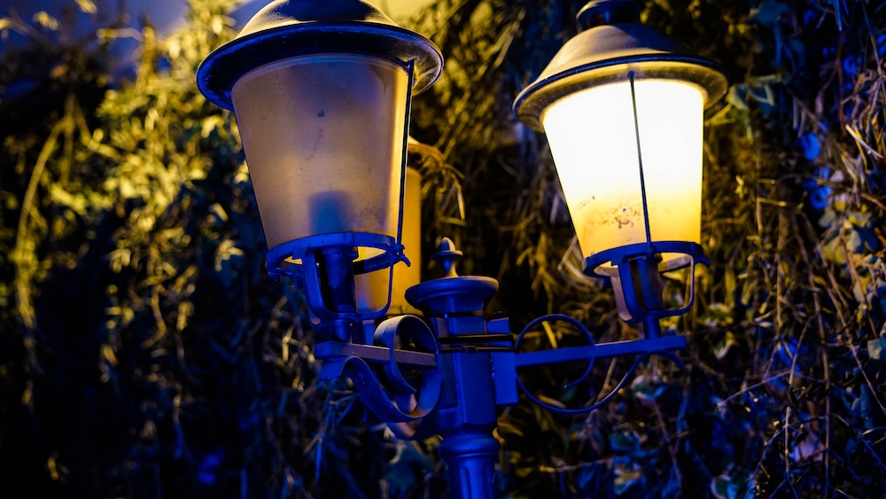 A lamp post with three lamps, only one is lit.