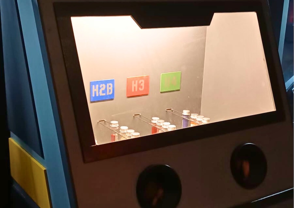 A glove box with test tubes filled with different colored materials.