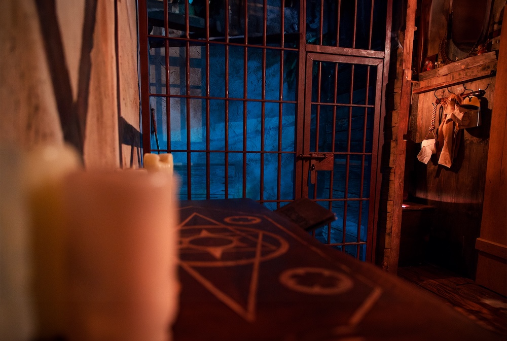 A room fillwed with magical objects, in the distance is a metal cage and door.