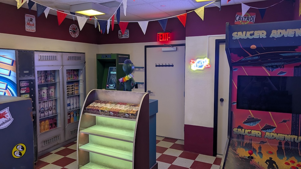 A convenience store with assorted items on the shelves and an arcade cabinet labeled, "Saucer Adventure"
