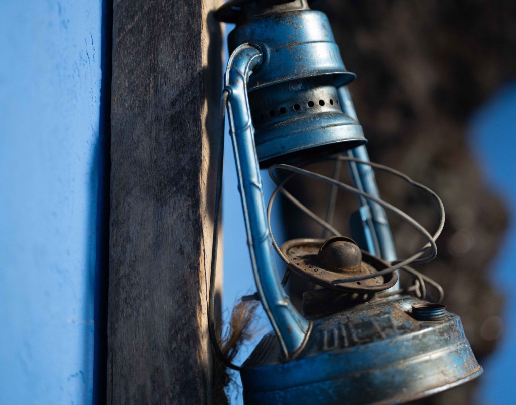 A dilapidated blue frame of a miner's lantern hangs crooked on the wall