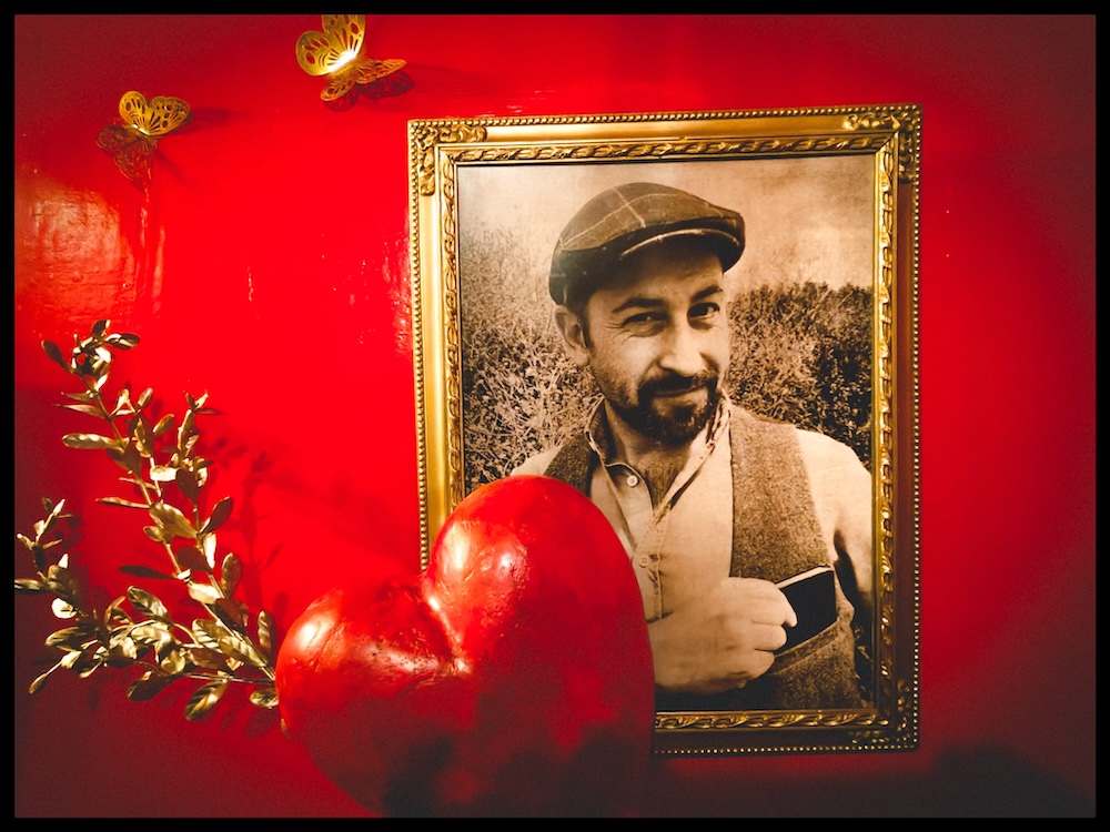 A gilded frame of a dapper, bearded man, with a large heart in front