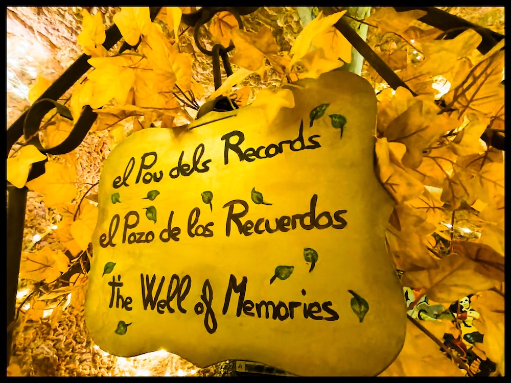 A sign in 3 languages that reads "The Well of Memories"
