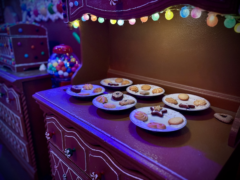 Plates of cookies on a gingerbread cabinet.