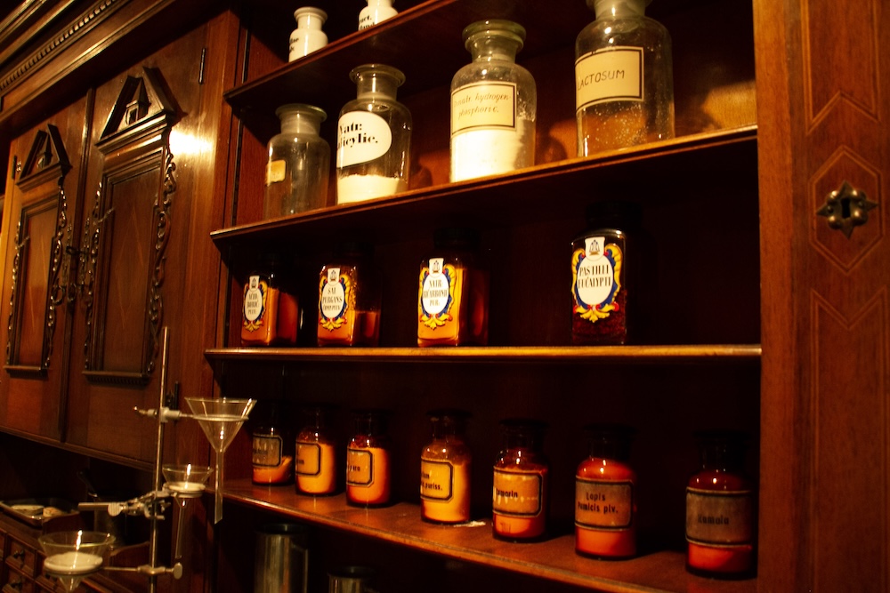 Wooden shelves filled with glass bottles in an old pharmacy.