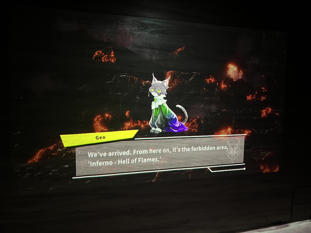 Geo, a cat character with glasses and a rainbow robe with ruffled collar and cuffs, appears against a background of a craggy mountain landscape dotted with fire and lava. Geo's dialogue box says "We've arrived. From here on, it's the forbidden area, 'Inferno - Hell of Flames'".