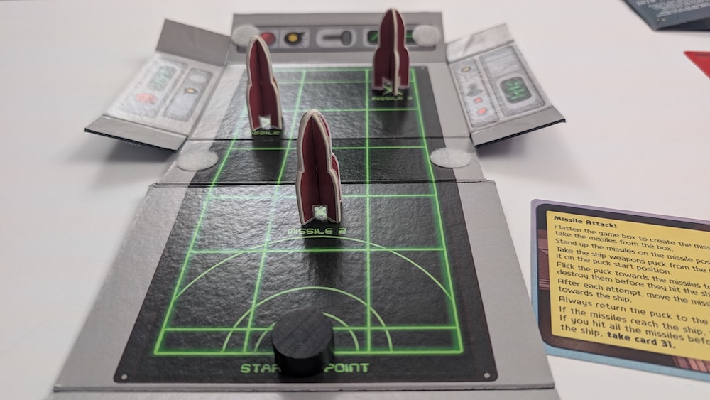 3 spaceship game pieces on top of an unfolded game board.