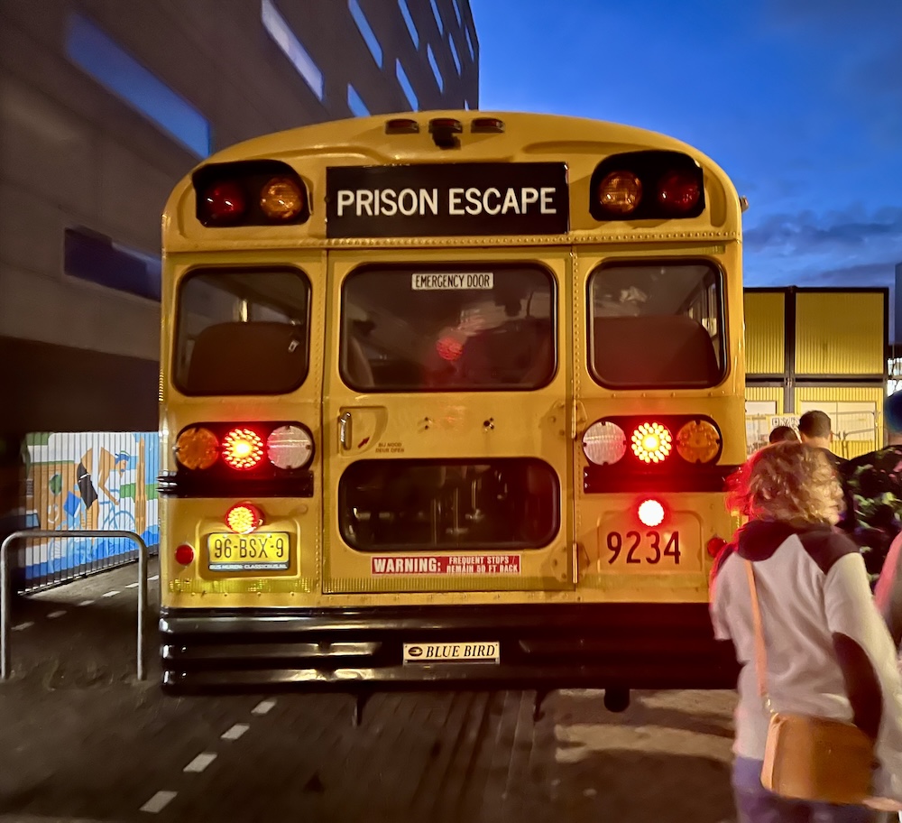The rear of a yellow school bus with a sign that reads, "Prison Escape"