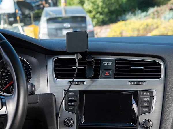 A magnetic car mount hanging from a vent. It has a cable running down from the bottom.