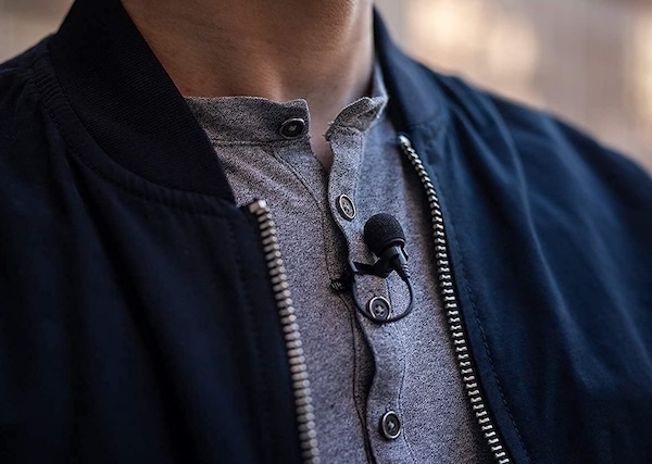 A small lavalier microphone attached to a person's shirt, just below the neckline.