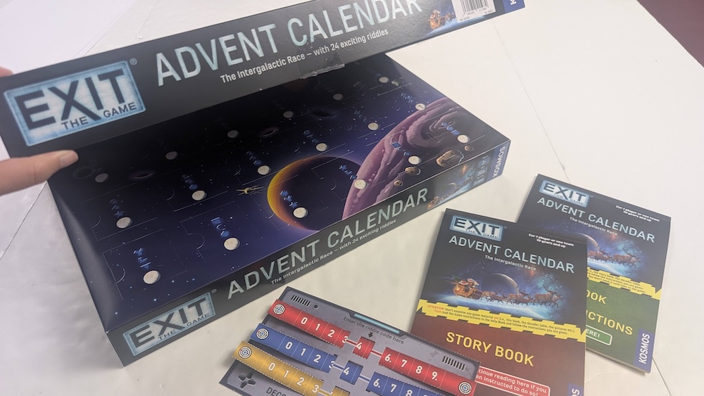 EXIT The Game Advent Calendar, "The Intergalactic Race" open revealing an advent calendar and assorted instructions, story materials, and an answer checker device.