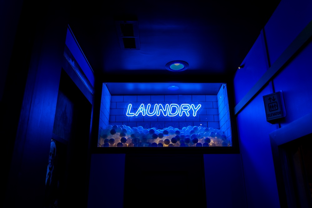 A large ball-pit labeled "Laundry" in blue neon in a dark room.