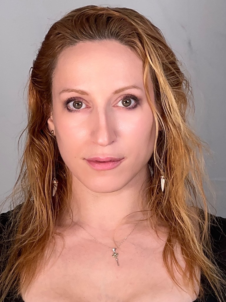 woman with wavy dark blonde hair with soft enigmatic smile.