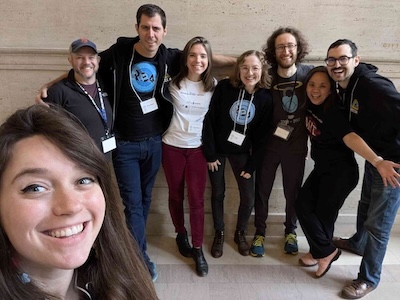 8 members of the REA team posing together in a marble hallway.