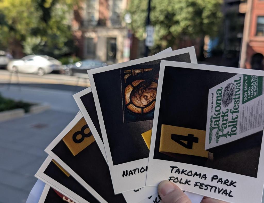 A hand fanning out a collection of polaroid pictures of a crime scene while out on a city street.