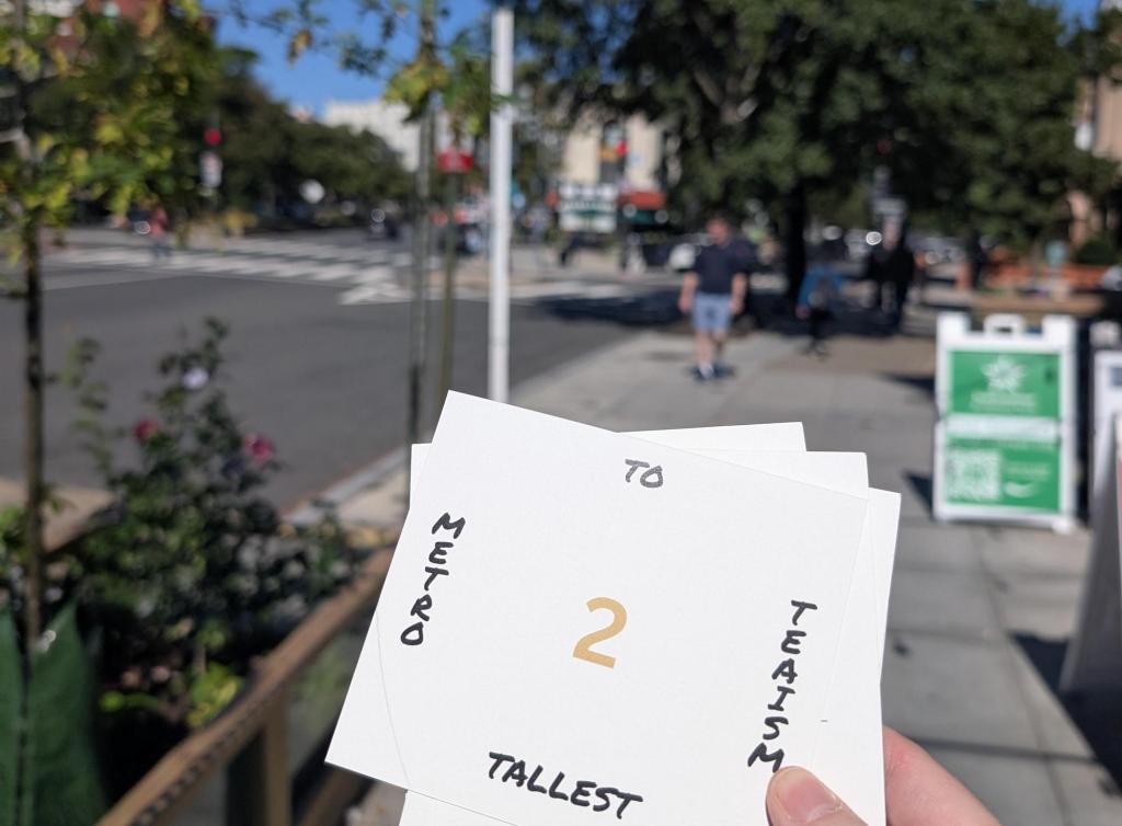 A card containing clues about a specific location being held while walking in a city street.