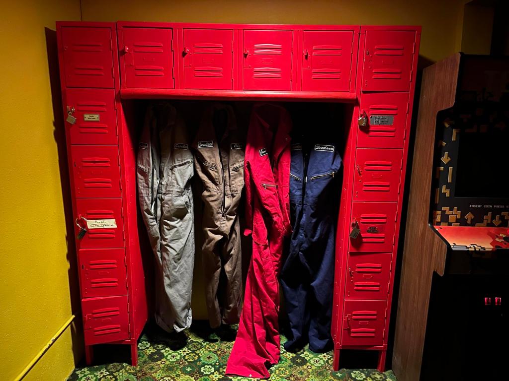 Wall of bright red lockers with jumpsuits hanging below the lockers.