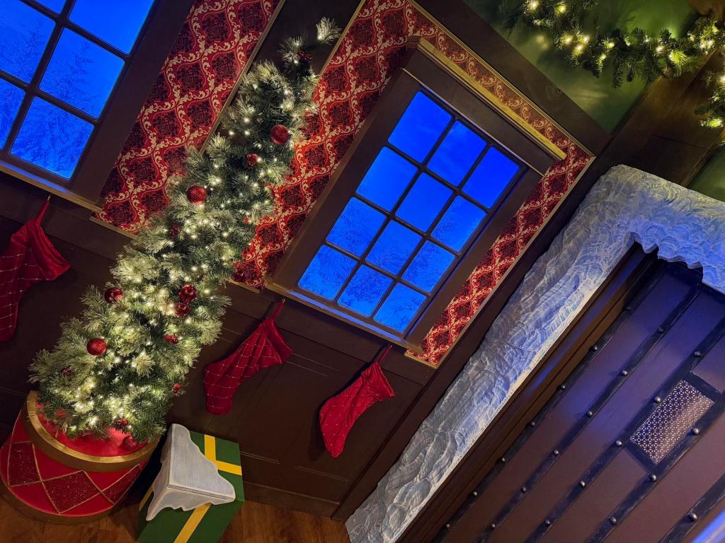 A Christmas tree with a present below it. Beside the tree is a large door that is frozen shut.