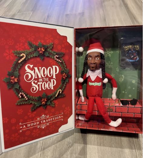 toy of a black man with long braids dressed in a red elf outfit sitting on a faux brick seat