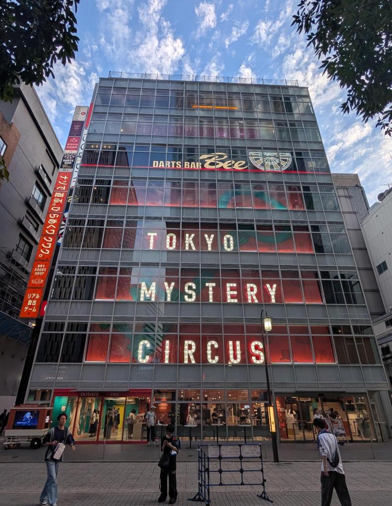 A six-story building with "Tokyo Mystery Circus" written in colorful lights on the front