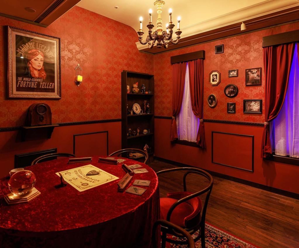 A red wallpapered room with a ouija board on a circular table