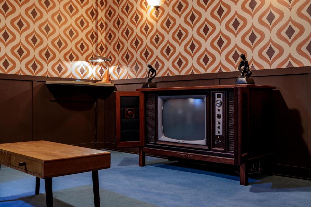 A 1960s living room with funky wallpaper and a retro TV set