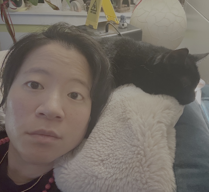 Headshot of Jacky resting her head against her cat.