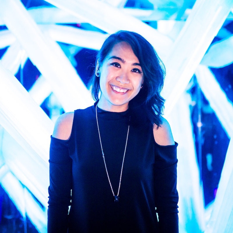 Headshot of Kat Lat standing in front of a structure of glowing light.