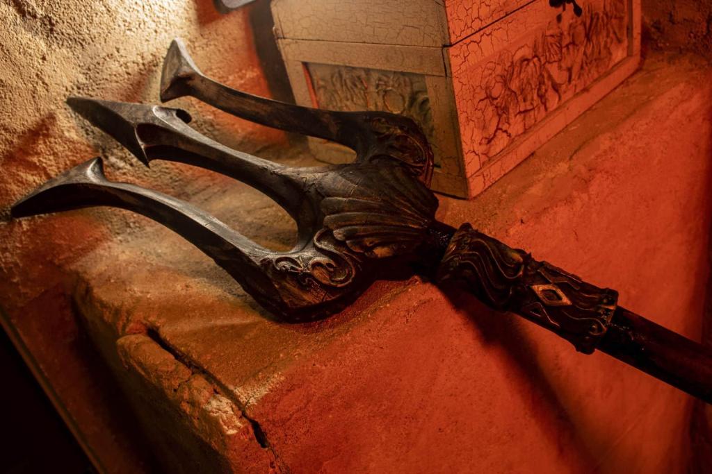 A trident leaned up against a weathered stone ledge