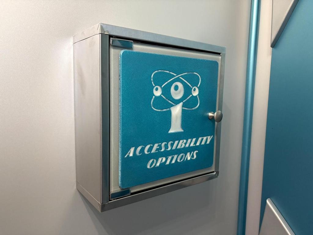 A square metal cabinet with a light blue door and a white IntelliCo logo. The words Accessibility Options are etched in white on the door.
