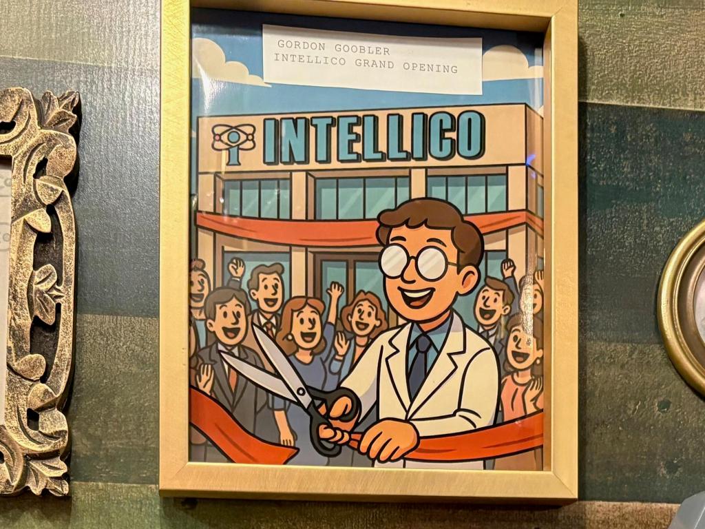 Gold framed cartoon image of a man in a white lab coat, cutting a red ribbon in front of the IntelliCo building. A crowd is cheering behind him. A white label at the top of the picture reads "Gordon Goobler IntelliCo Grand Opening"