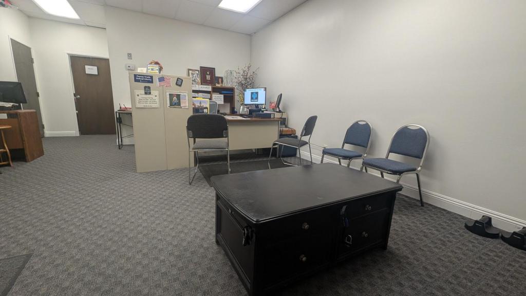 A tax preparer's office showing a desk with computer and chairs, a waiting area, and a coffee table console with locks securing its drawers.