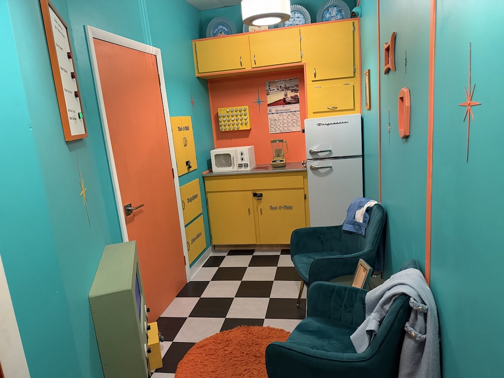 A blue, yellow, and orange 1950s style combined kitchen and living room.