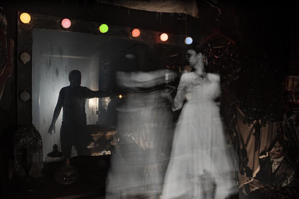 A ghost in front of a backstage dressing room mirror