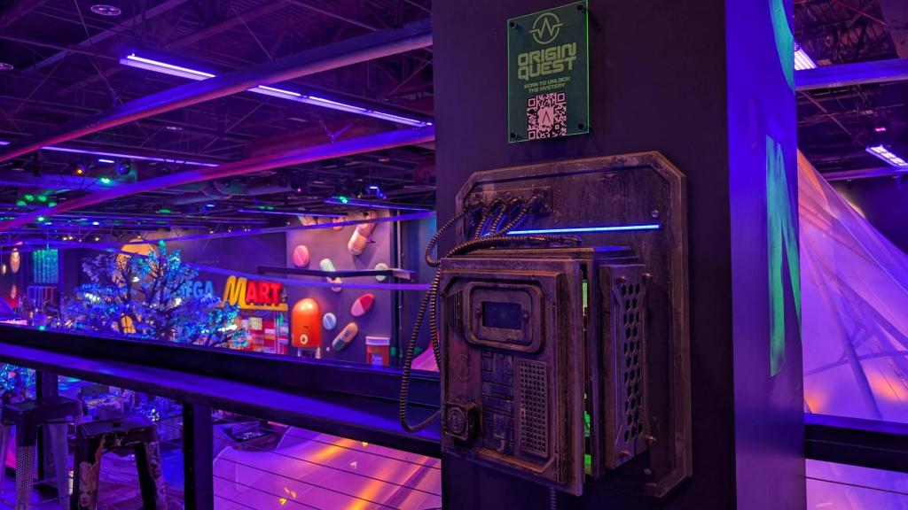 A panel box is mounted on the wall, over which is a sign for Origin Quest and a QR code to "unlock the mystery"