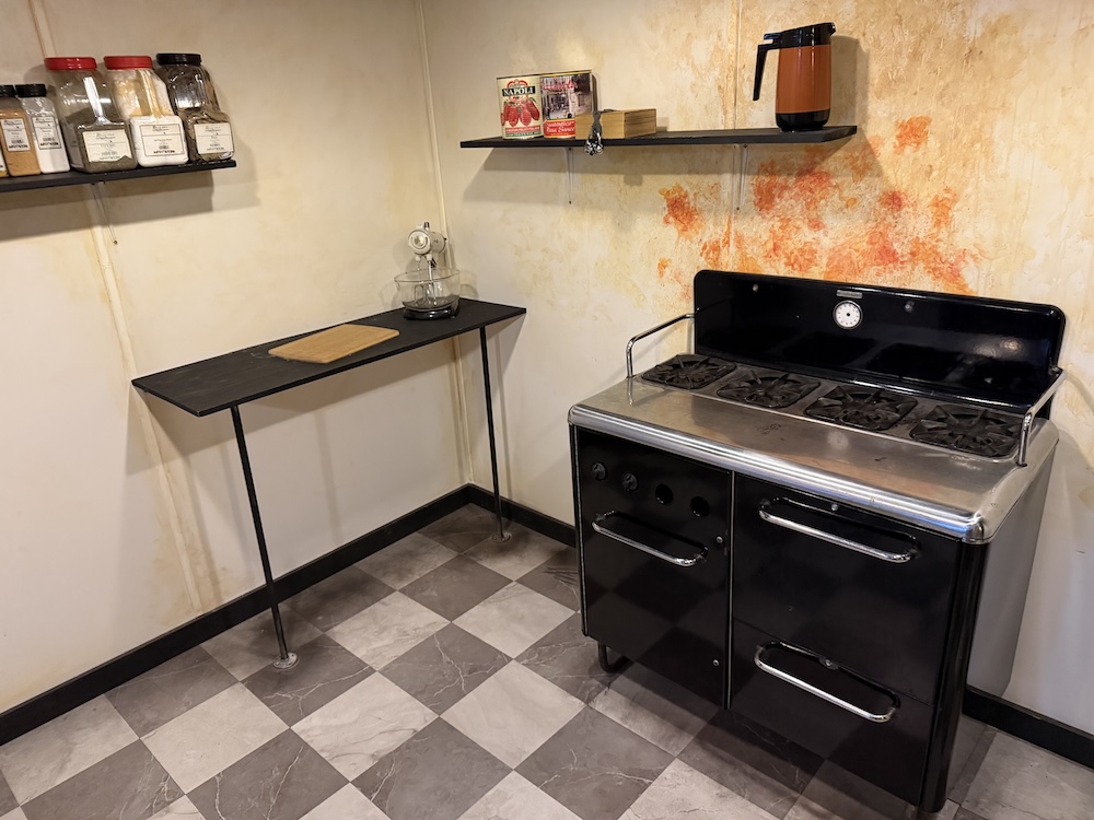 An old dirty kitchen in an Italian American restaurant. Red sauce stains the wall behind the range.