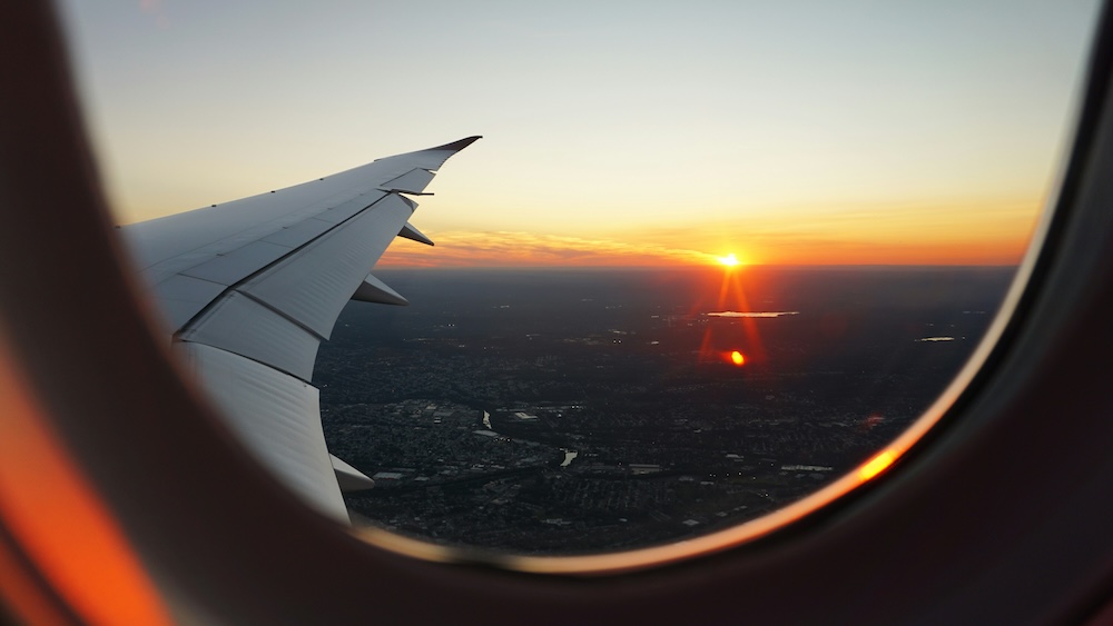 View of an airplane wing through a window at sunset.