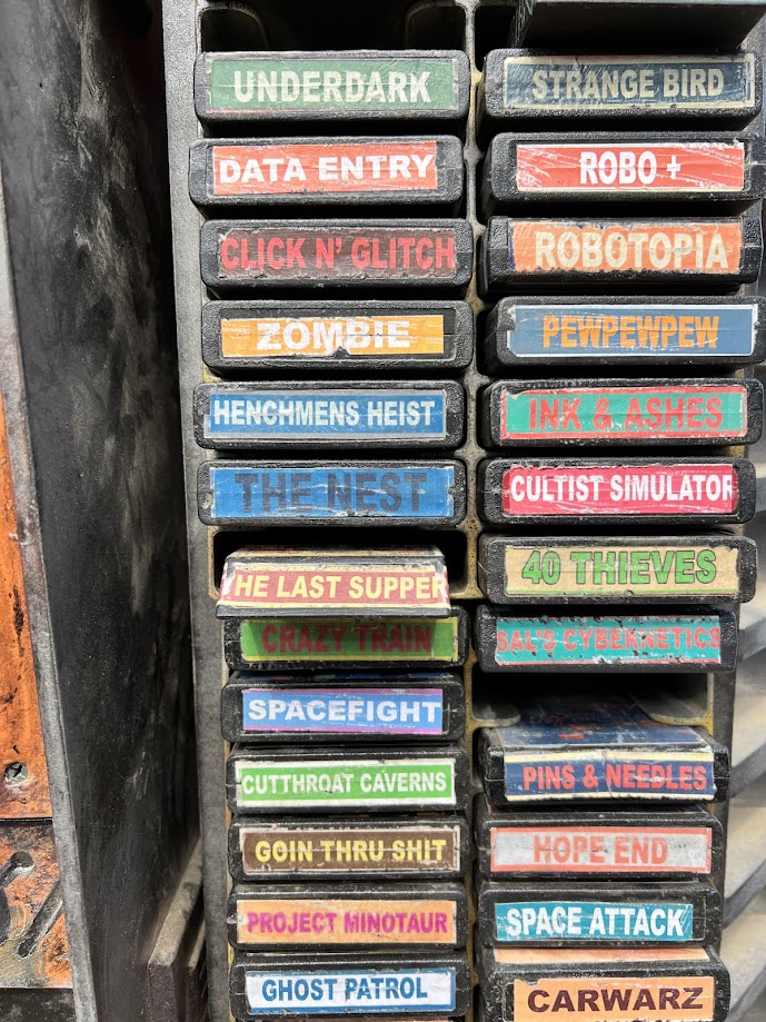 Atari cartridges in a shelving unit with names from famous escape rooms
