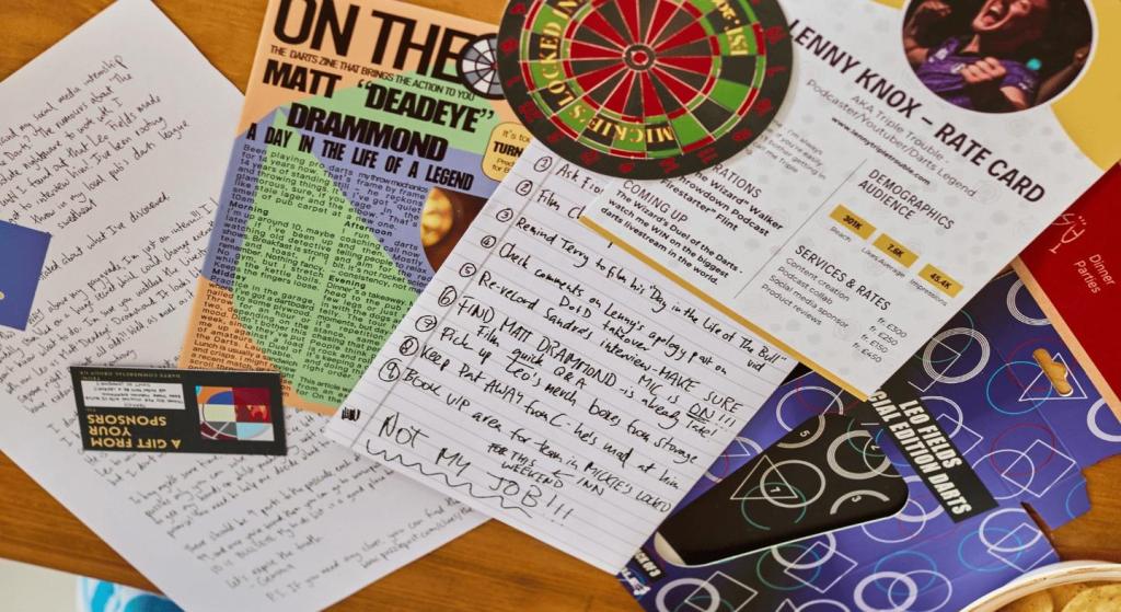 paper-based puzzle materials including notes, a magazine page, a business card, etc spread out on a table