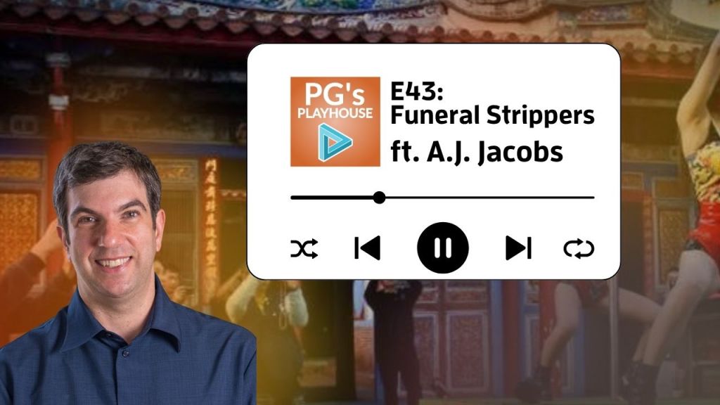 man with side parted hair and button down blue shirt. Background of chinese temple, girls dancing and people taking photos