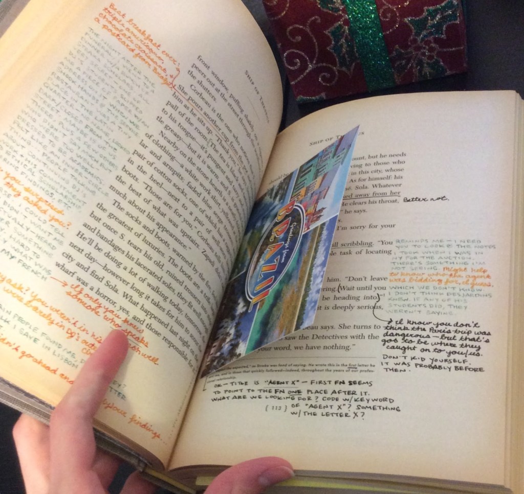 close up of book with writing in margins and postcard sandwiched between pages