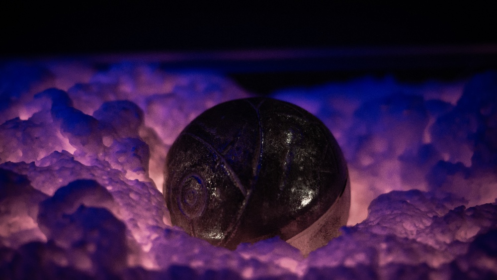 Closeup of an unusual carved orb resting on a glowing material.