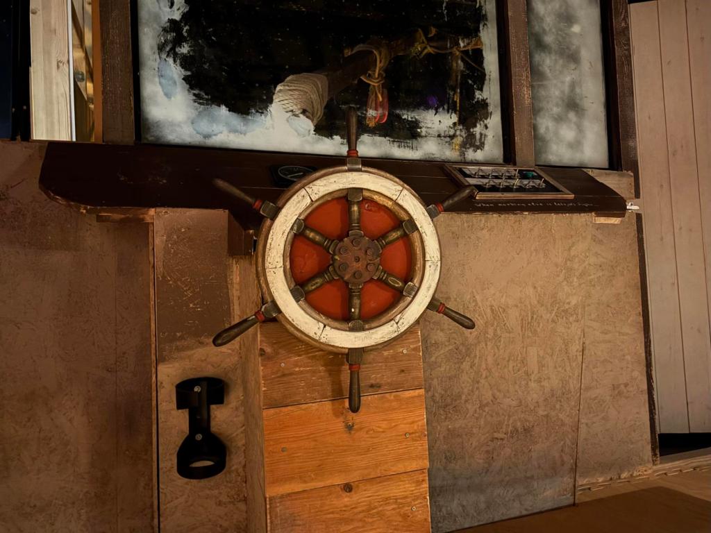 Closeup of a ship's wheel with a frosted window above it, and a set of toggle switches on the side.