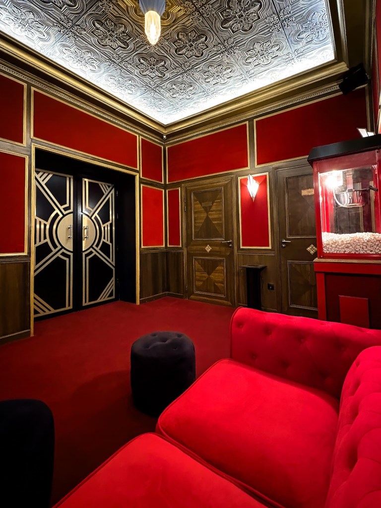 The waiting area outside of a magnificent art deco movie theater.